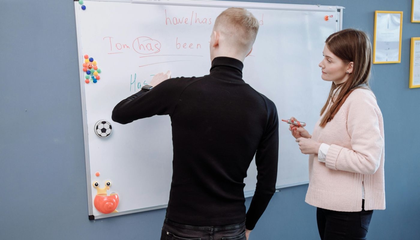 a female teacher teaching English to her male student