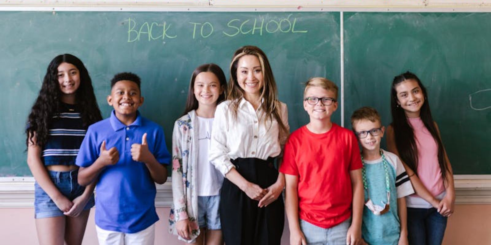 children standing in front with their teacher