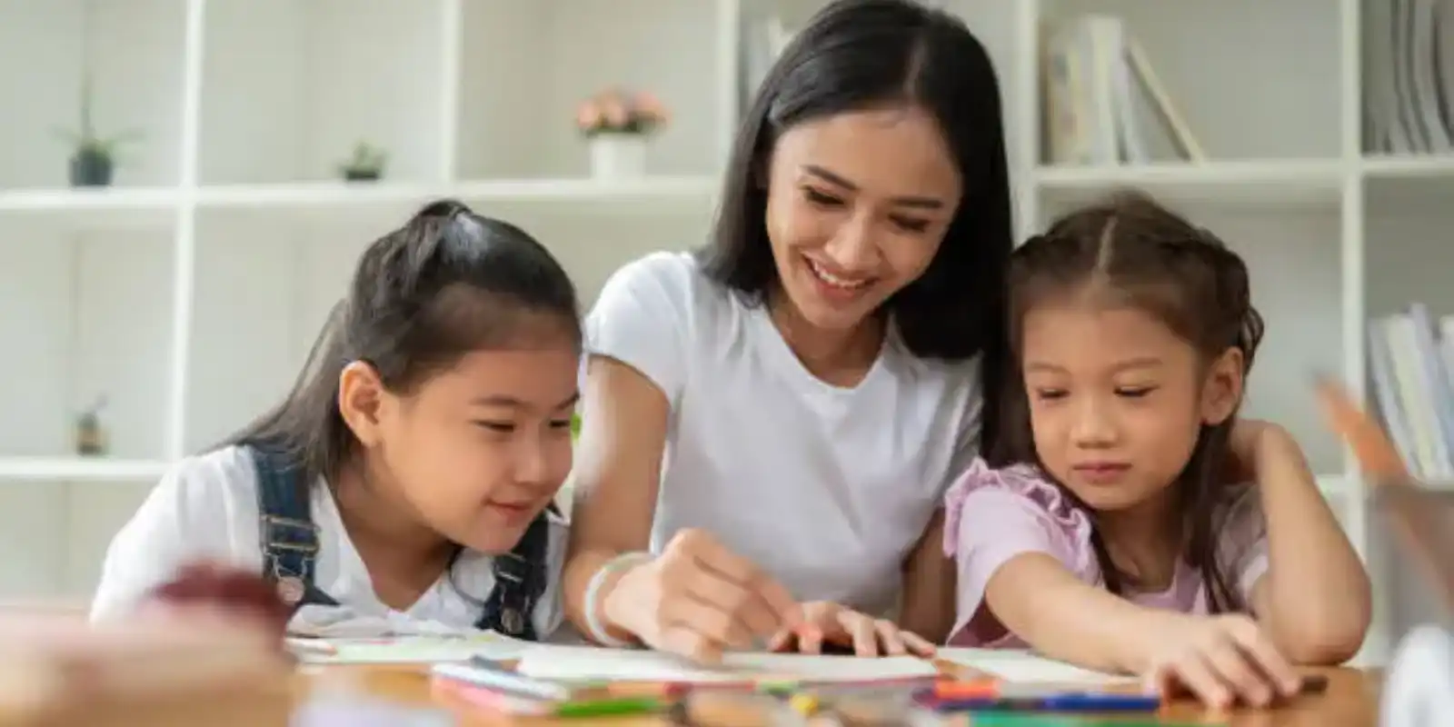 A happy female teacher teaching two young kids