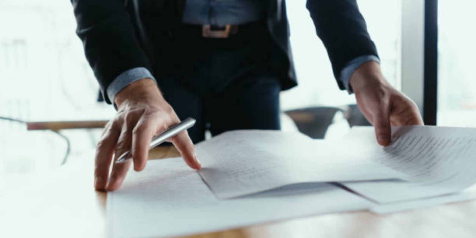 Close up hands signing documents in a modern office