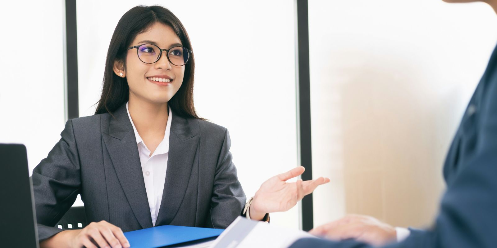 Two people are seated at a desk during a job interview.