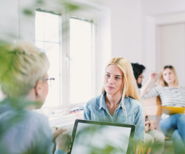 Two women talking in bright room