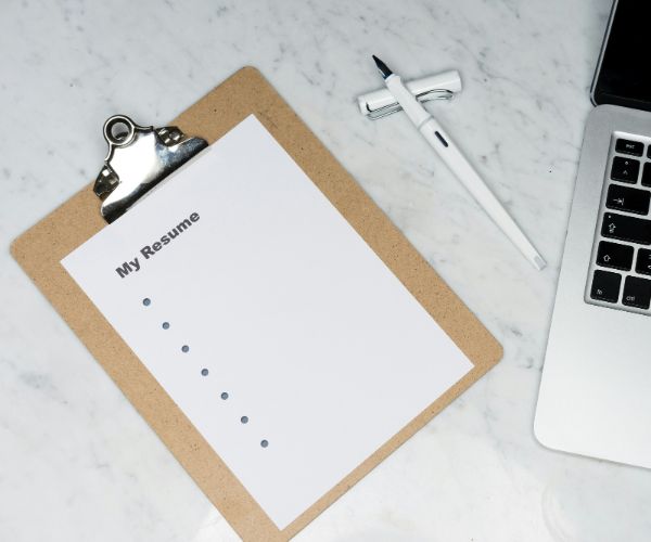 Resume on clipboard beside laptop